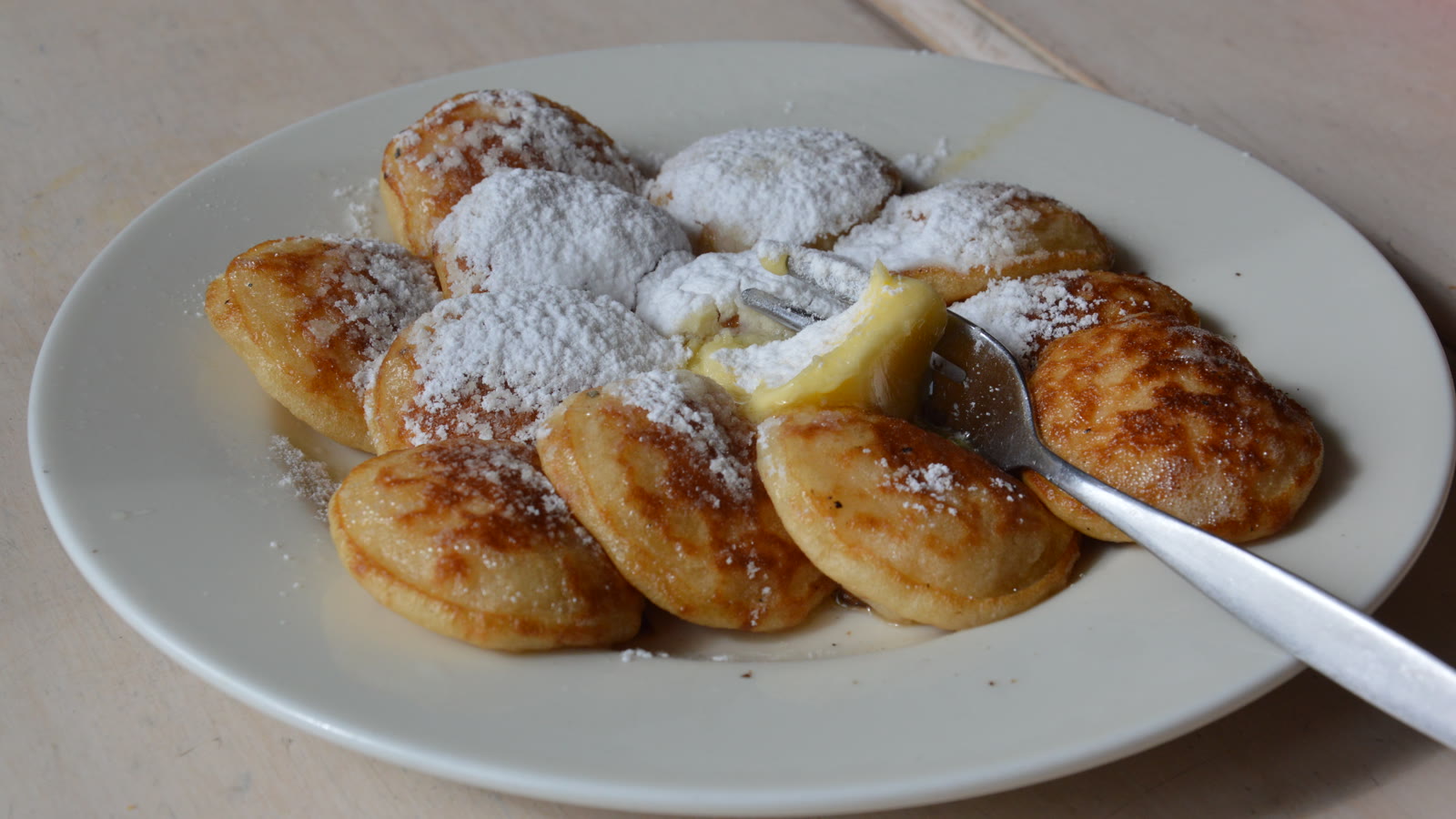 Tallerken med små hollandske poffertjes drysset med flormelis og en klat smør